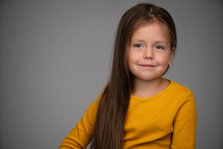 Adorable six years old girl isolated on white studio background, pretty brown-haired fringe hairstyle european appearance child pose indoor smiling look at camera, generation Z conceptの写真素材