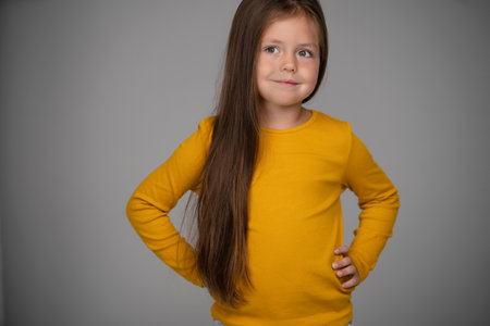 Adorable six years old girl isolated on white studio background, pretty brown-haired fringe hairstyle european appearance child pose indoor smiling look at camera, generation Z conceptの写真素材
