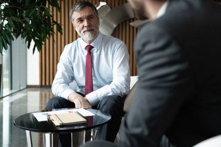 Businessmen discussing deal, sharing startup ideas, business partners negotiations or job interview in modern office, colleagues talking, working on project togetherの写真素材