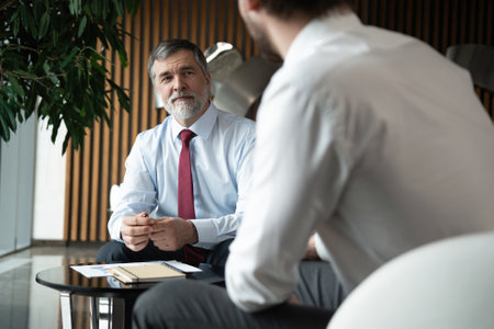 Businessmen discussing deal, sharing startup ideas, business partners negotiations or job interview in modern office, colleagues talking, working on project togetherの写真素材