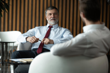 Businessmen discussing deal, sharing startup ideas, business partners negotiations or job interview in modern office, colleagues talking, working on project togetherの写真素材