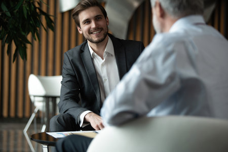 Businessmen discussing deal, sharing startup ideas, business partners negotiations or job interview in modern office, colleagues talking, working on project togetherの写真素材