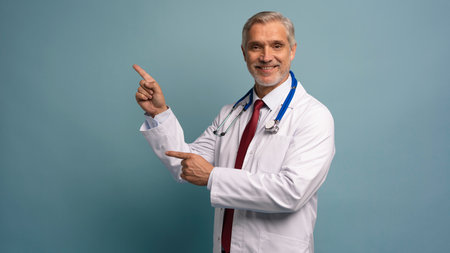 Handsome doctor man wearing medical uniform over isolated background smiling cheerful presentingの写真素材