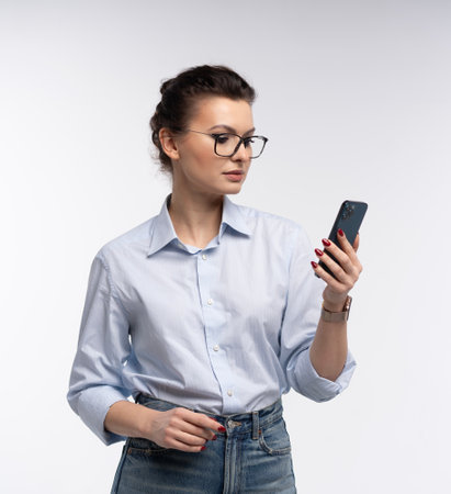 Smiling business woman in eyeglasses holding smartphone and using over white backgroundの写真素材
