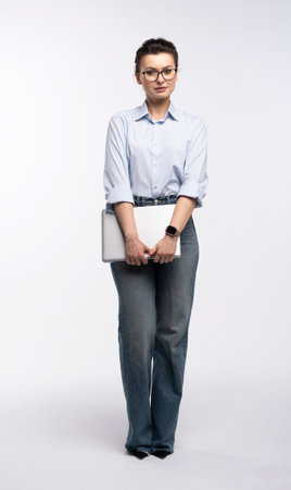 Full length of portrait of a smiling businesswoman carrying laptop computer standing isolated over white backgroundの写真素材
