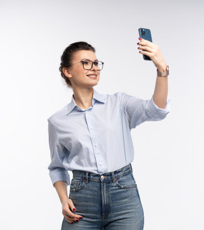 Smiling business woman in eyeglasses holding smartphone and using over white backgroundの写真素材