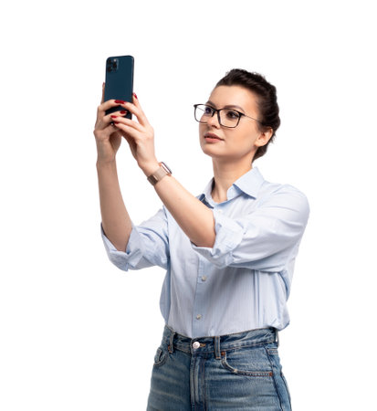 Smiling business woman in eyeglasses holding smartphone and using over white backgroundの写真素材
