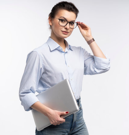 Portrait of a smiling businesswoman carrying laptop computer standing isolated over white backgroundの写真素材