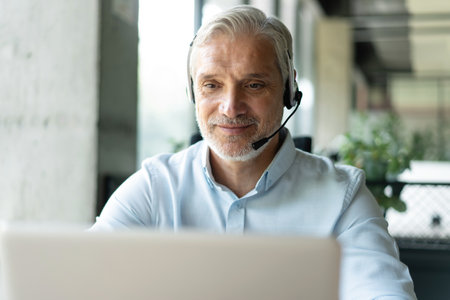 Smiling businessman using headset when talking to customer. Tech support manager in headset...