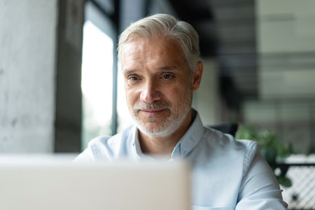 Mature 40s focused businessman, executive director working using laptop sitting at officeの写真素材