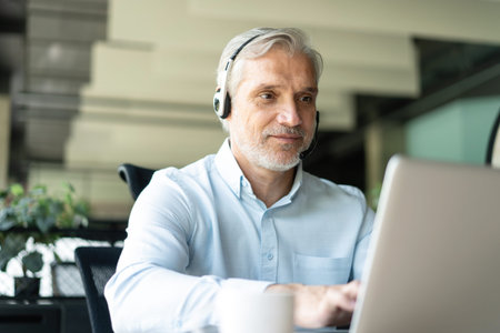 Smiling businessman using headset when talking to customer. Tech support manager in headset...