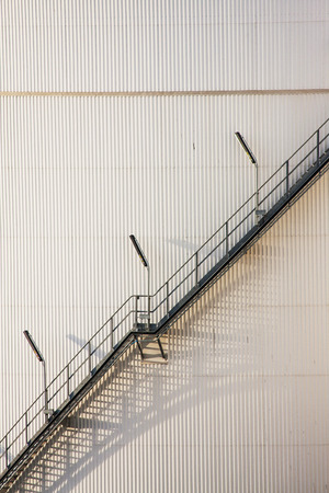 Steep Stairway Rising Alongside Round Oil Storage Tankの写真素材