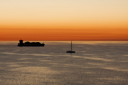 Containership and Sailboat Sailing Together at Dawn