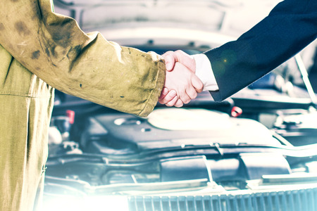 Businessman and Mechanic Handshaking in Front of a Carの写真素材
