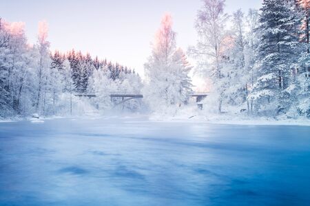 Bridge Crossing Flowing River in Frosted Rural Landscape 