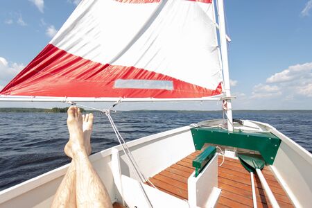 Sailing Relaxed with Small Sailing Boat Laying Feet on Boardの写真素材
