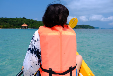 A woman paddling kayak on blue sea on the beach at Gulf of Thailand.