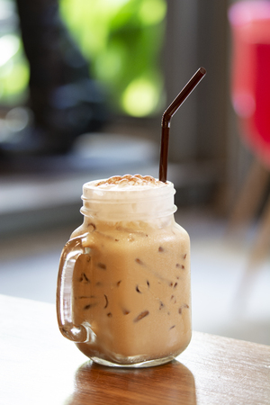 Milk tea mixed with whipped cream on wooden floorの写真素材