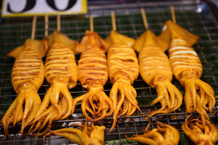 Grilled squid placed on a grill for sale in the market.の写真素材