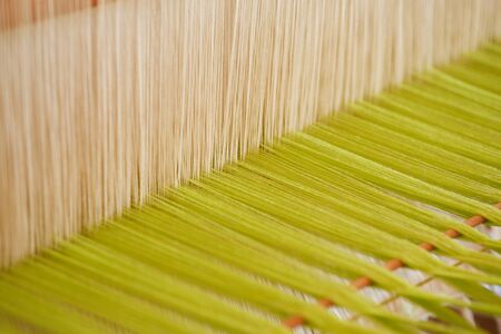 Close Up green and white yarn on the loom. Native cotton weaving using a Loom of weaving, which is folk wisdom, showing the ingenuity in creating Thai art.の写真素材