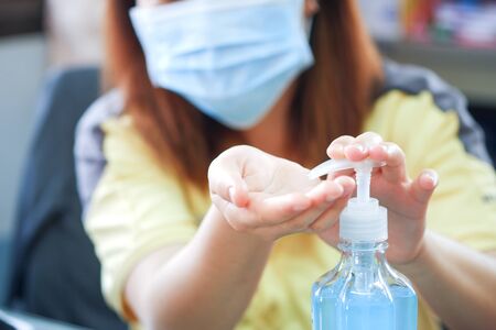 Asian women using alcohol antiseptic gel and wearing prevention mask,prevent against infection of Covid-19 outbreak, Coronavirus prevention remove and kill bacteria, germ and virus.の写真素材