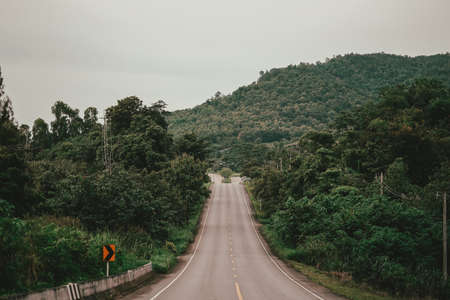 A view of the main road in the countryside with hills and covered with forests, both side.の写真素材