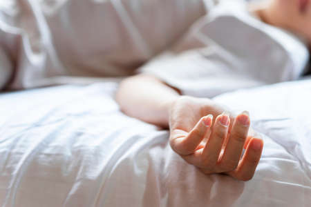 Woman committing suicide in bed, focus on the hand of dead body. The concept of die alone.の写真素材