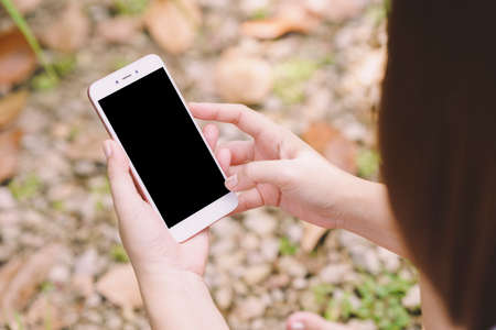 Woman pressing her finger on phone with blank black screen for text input on blurled background.の写真素材