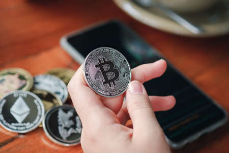 Maesot, Thailand- June 13, 2021:Hand of woman's holding Bitcoin and smartphone showing stock chart...