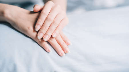 The woman's hands or nails are placed on a light blue cloth. Nail health care concept.の写真素材