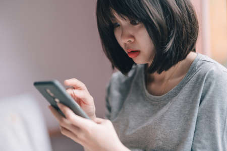 A woman looks shocked when she sees something on her phone.