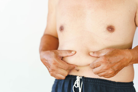 Man's hand squeezing belly fat. Fat accumulation in the abdomen of men. People with high body fat accumulation.の写真素材