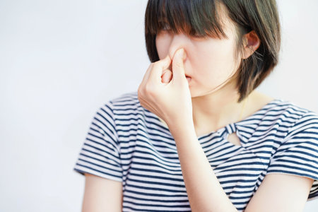 Woman showing dislike of bad smell by covering her nose.の写真素材