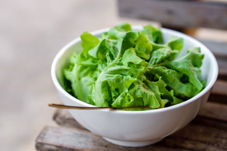 Leafy greens or lettuce in white bowls that are commonly used in salads or eaten fresh. Healthy food...