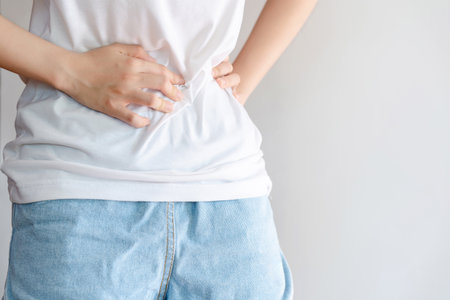 Woman in white shirt holding her stomach because of pain. Health care concept.の写真素材