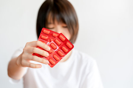 Asian woman holding unlabeled pills on white background. Selective focus.の写真素材