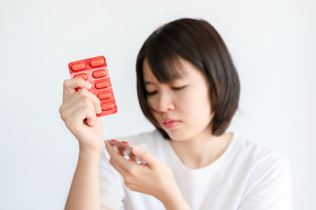 Woman reading the name of the medicine and holding the medicine in her hand.の写真素材