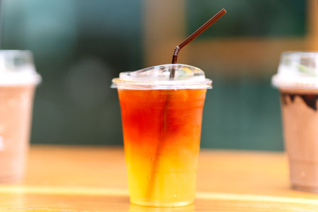 Lemon tea in a plastic glass with straws on the table.の写真素材