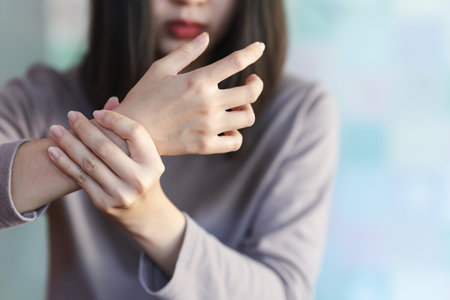 A woman touches her arm or wrist because of pain from a health problem. Health care concept.の写真素材