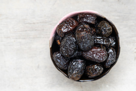 Ajwah dates in a ceramic bowl on a white wooden background are the best fruits of Medina.