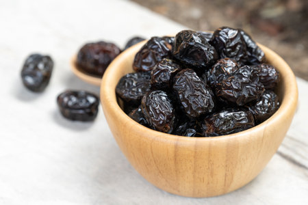 Ajwah dates in a wooden bowl on a white wooden background are fruits used to break the fast for...