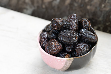 Ajwah dates in a ceramic bowl on a white wooden background are the best fruits of Medina.