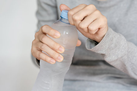 A person opening a plastic water bottle, emphasizing hydration and convenience in everyday life.の写真素材