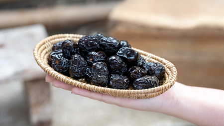 A hand holding a woven basket filled with dried Ajwah dates that Muslims eat to break their fast in...