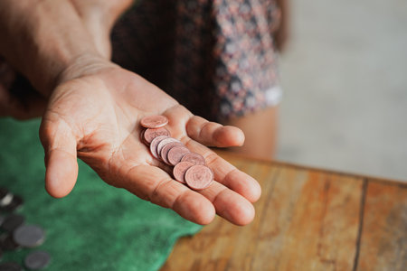 A close-up of a hand holding a handful of coins on a wooden table, symbolizing finance and savings....