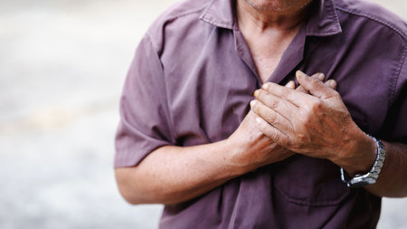 Experiencing chest pain, man clutches his heart in distress.の写真素材