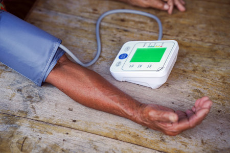 Monitoring blood pressure is essential for health management, especially for elderly. This shows close up of arm with blood pressure monitor, highlighting importance of regular health checks.の写真素材