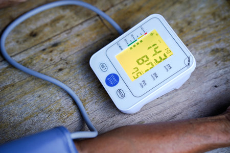 digital blood pressure monitor displaying systolic and diastolic readings on wooden surface, emphasizing health monitoring and wellness.の写真素材