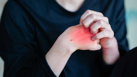 image depicts person holding their wrist with noticeable red mark, suggesting discomfort or...