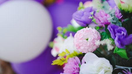 A vibrant arrangement of colorful flowers, complemented by a white balloon and purple backdrop, creating a festive atmosphere.の写真素材
